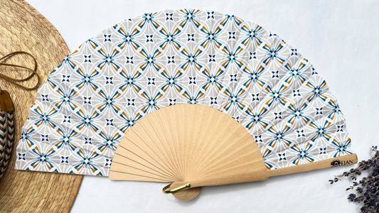 Éventail Estelle en coton aux motifs géométriques bleus et beiges avec monture en bois naturel, confectionné artisanalement en Provence.