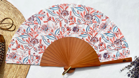 Éventail Rosalie en coton à motifs floraux corail, bleu et terracotta avec monture en bois naturel, fabriqué artisanalement en Provence.